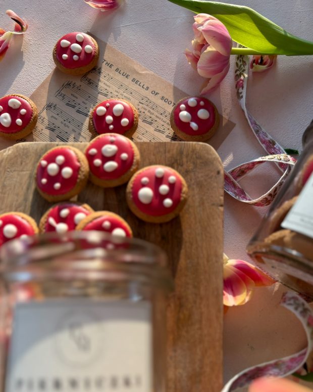 Pierniczki Muchomorki rozsypane ze słoika na desce.