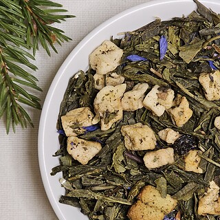 Zielona herbata Sencha Marcepanowe Jabłko z jabłkiem, marcepanem i cynamonem na białym talerzyku, w świątecznej aranżacji.