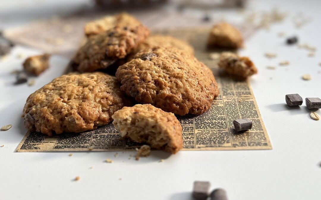 Ciasteczka owsiane rozsypane na stole, w tle paczka ciastek