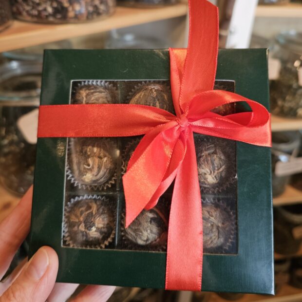 Zawiązana czerwoną kokardą bombonierka zawierająca kule herbaciane.